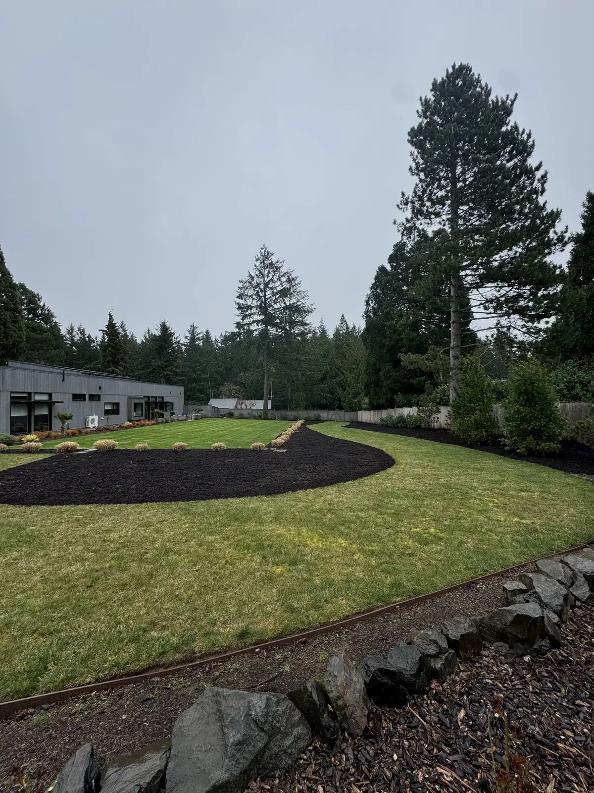 Finished Wilsonville-area landscape bed with stone, plants, and clean edging by CreekView Landscape