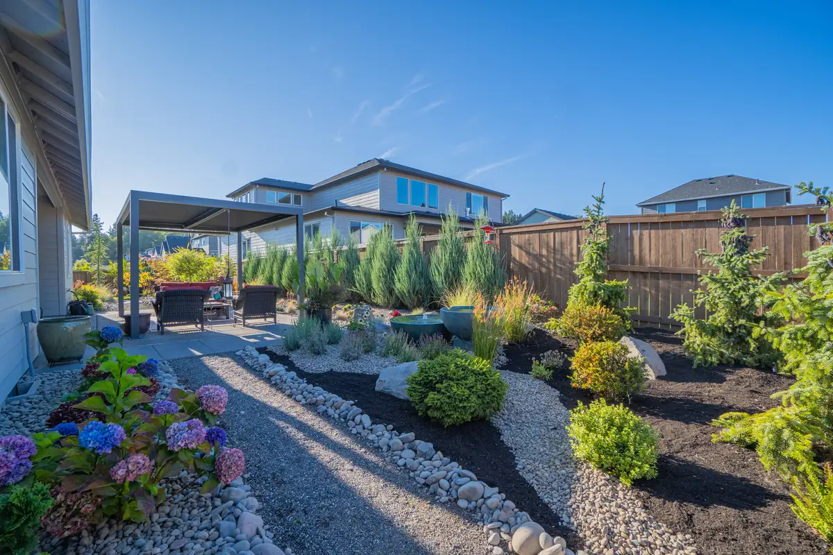 Backyard landscape with pergola and hydrangeas by CreekView Landscape
