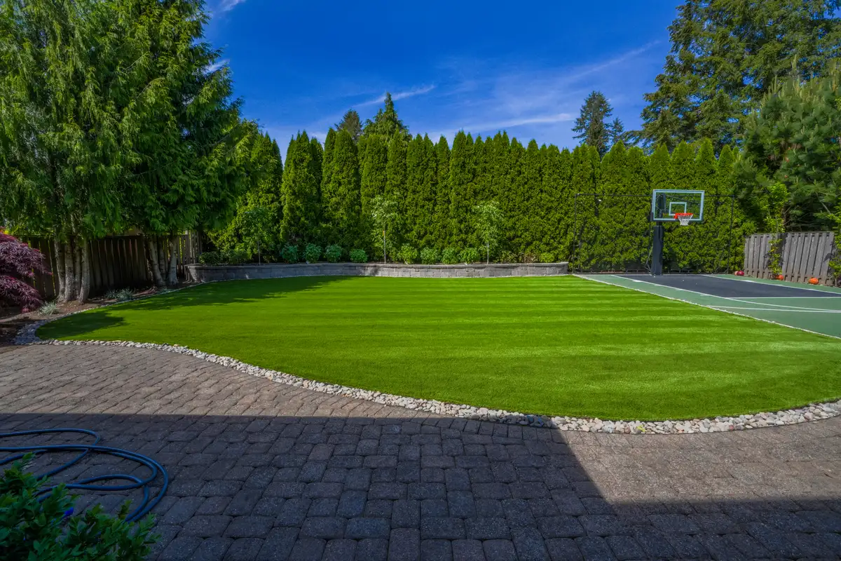 Luxury backyard artificial turf installation with blue sky by CreekView Landscape