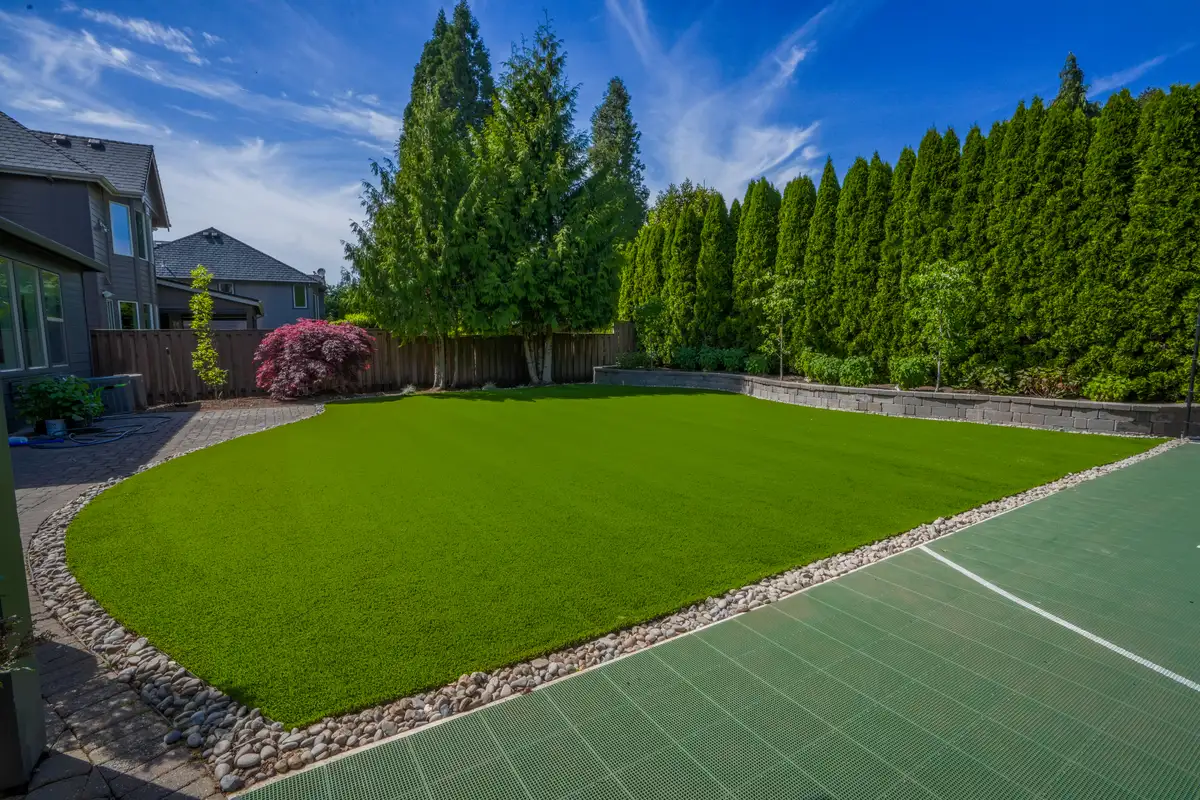 Wide-angle turf installation with retaining wall by CreekView Landscape in Oregon